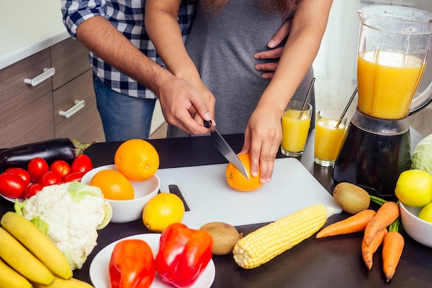 Estilo de vida saludable y ecológico. mujer india feliz con su marido haciendo batido en la cocina grande.