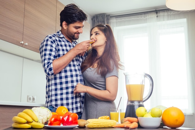 Estilo de vida saludable y ecológicomujer india feliz con su esposo haciendo batido en la cocina grande