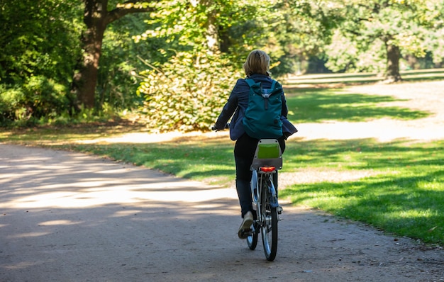 Estilo de vida saludable La mujer está montando en bicicleta en un camino del parque Tiergarten Berlín Alemania Fondo de naturaleza