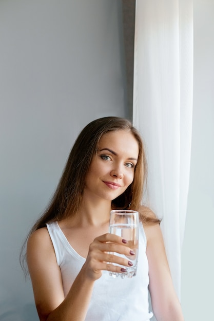 Estilo de vida saludable Mujer joven bebiendo de un vaso de agua dulce