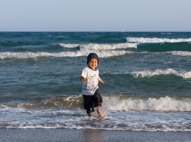 Estilo de vida saludable. Un niño camina y juega a la orilla del mar.