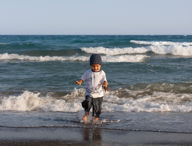 Estilo de vida saludable. Un niño camina y juega a la orilla del mar.