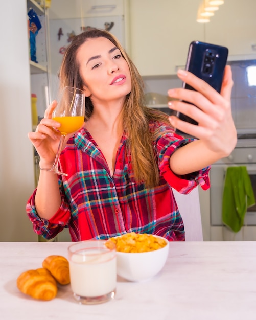 Estilo de vida saludable, rubia caucásica con un jugo de naranja para desayunar y grabar un video para redes sociales