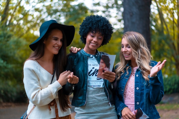 Estilo de vida. Tres buenas amigas en un parque divirtiéndose, una rubia, una morena y una chica latina con cabello afro