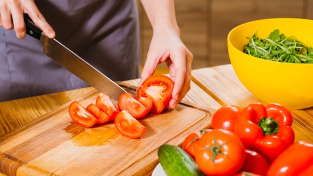 Estilo de vida vegetariano Captura recortada de mujer cocinando tomates picados para ensalada