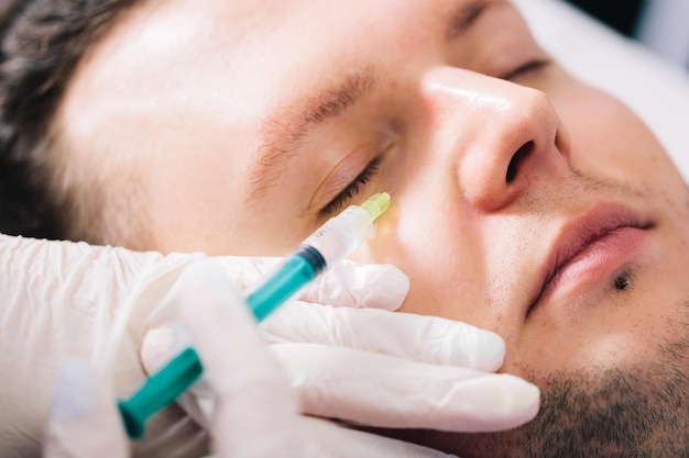 Foto estimulador de tejido inyectable en la cara del hombre en salón de belleza medicina estética