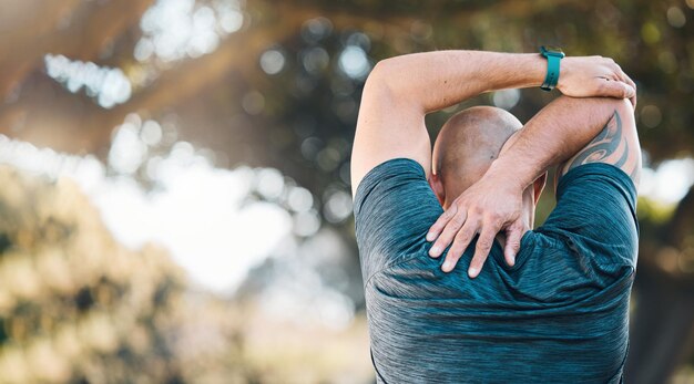 Estiramiento al aire libre y hombre en un parque con calentamiento deportivo y tensión muscular por el ejercicio físico y el ejercicio Problema de ejercicio persona masculina y espalda con masaje médico y fisioterapia para el entrenamiento