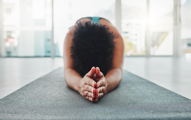 Estiramiento de brazos de yoga y manos de oración de una mujer negra en un gimnasio para relajarse zen y ejercitar la paz de Pilates y el entrenamiento de meditación de un atleta en posición de oración en el suelo sintiéndose tranquilo por el estiramiento