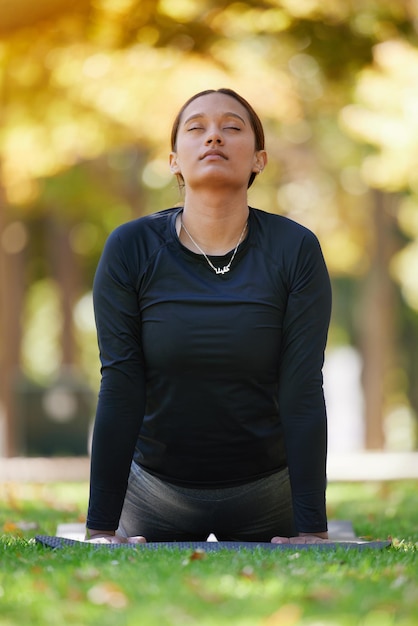 Estiramiento de cobra de yoga y mujer en el parque para la salud, el bienestar y la flexibilidad Zen chakra pilates pose y mujer con los ojos cerrados entrenando meditación y ejercicio y atención plena al aire libre