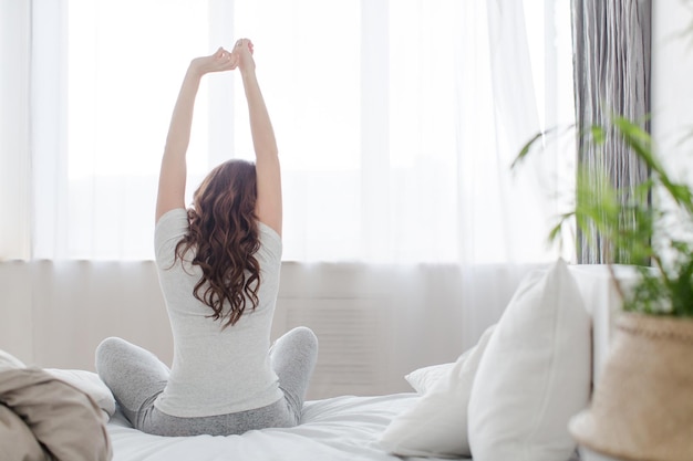 Foto estiramiento femenino sentado en la cama por la mañana