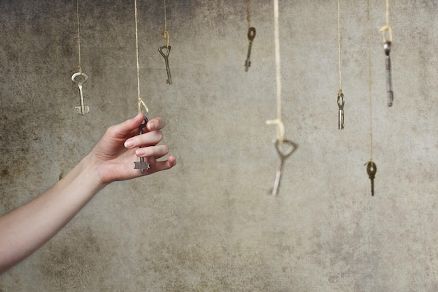 Foto estiramiento de la mano para una de las muchas llaves antiguas colgando de hilos