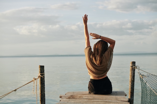 Foto estirar mujer sentada en el muelle