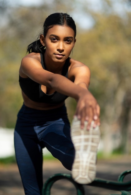 Estirarse bien previene las posibilidades de lesiones Retrato de una joven deportista estirando las piernas mientras hace ejercicio al aire libre