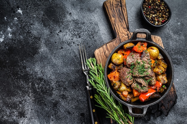 Estofado de carne en una olla sobre una tabla de cortar rústica oscura