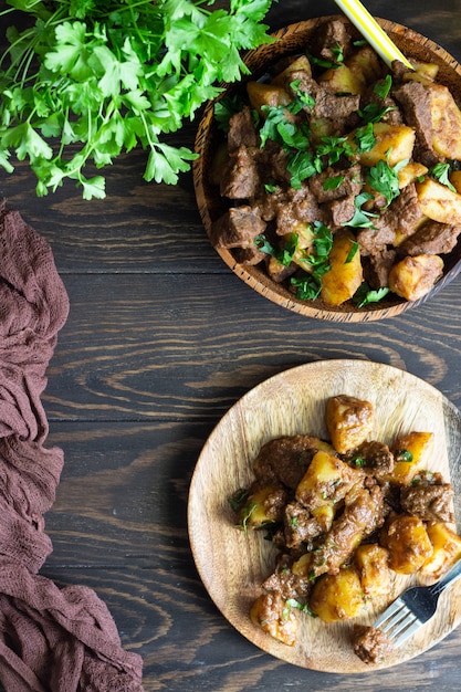 Estofado de carne con patatas y perejil en plato de madera. Estofado de carne portuguesa tradicional.