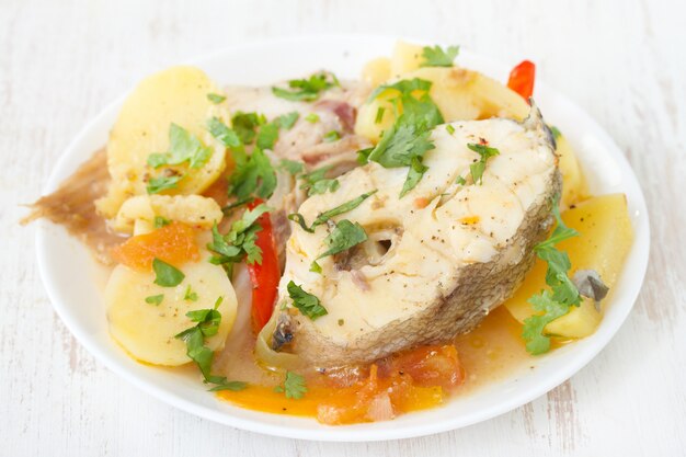 Estofado de pescado en un plato blanco sobre superficie blanca