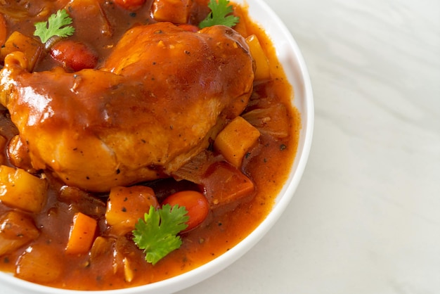 Foto estofado de pollo casero con tomates, cebollas, zanahorias y patatas en el plato