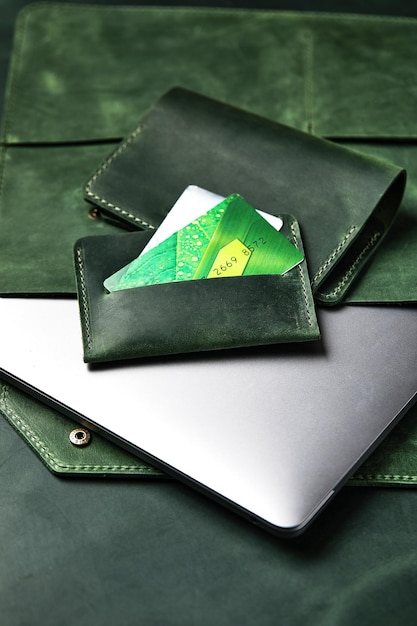 Estojo de couro para um porta-cartões de carteira de laptop de produtos artesanais de couro verde em uma mesa de madeira closeup