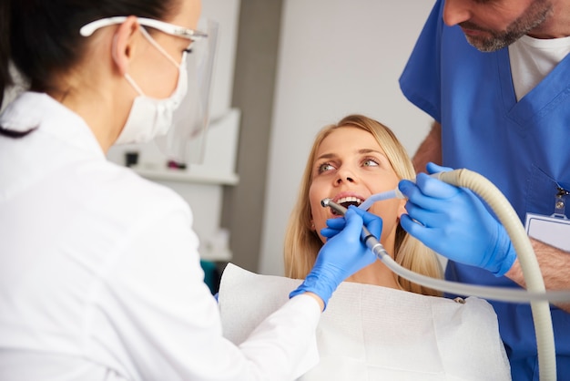 Estomatóloga y su asistente que trata a una mujer por caries dental.