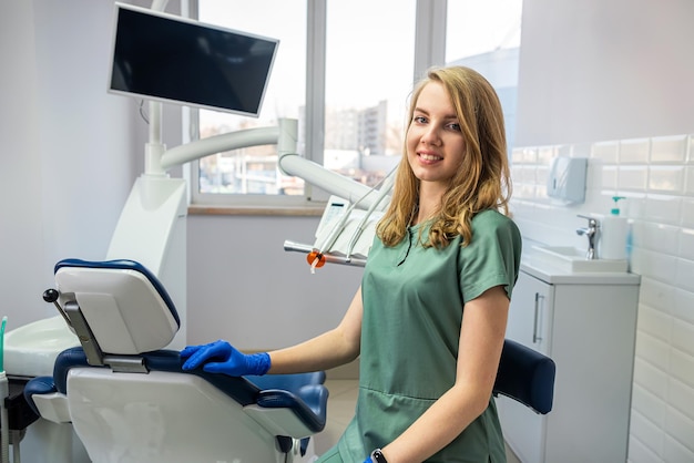 Estomatología de dentista bastante joven en uniforme y guantes en el gabinete del lugar de trabajo médico amable