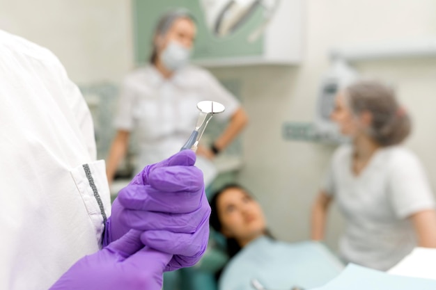 Estomatólogo mano en guantes de goma tomando instrumento médico profesional para el examen del paciente