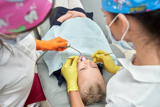 Estomatólogos en gorras médicas que curan los dientes de los niños.