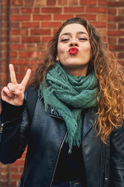 Estou com um humor feliz e sortudo foto recortada de uma jovem atraente posando contra uma parede de tijolos