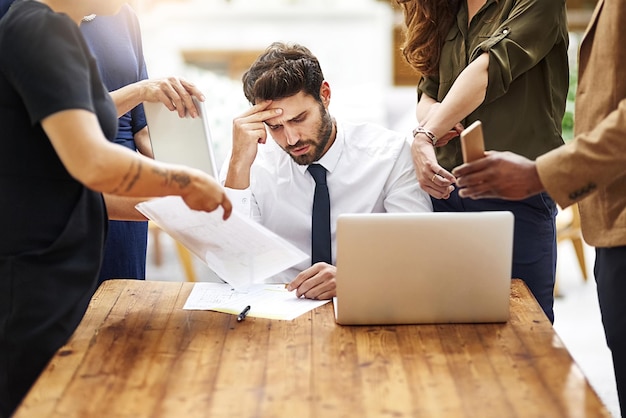 Foto estou seriamente tão estressado agora foto recortada de um empresário estressado cercado por colegas que precisam de ajuda em um escritório