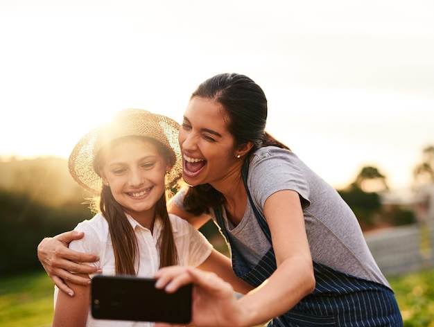 Estou tão orgulhoso de você foto recortada de uma jovem atraente e sua filha tirando selfies enquanto trabalhava na fazenda da família