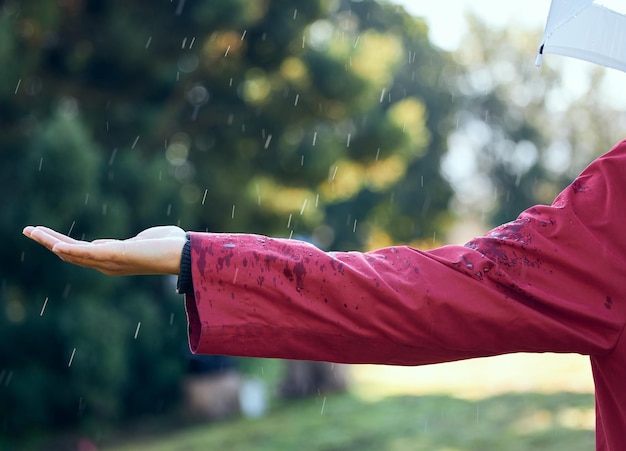 Estoy afuera bajo la lluvia. Toma de una mujer extendiendo su mano para sentir la lluvia afuera.