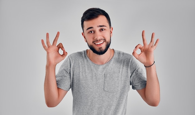 Estoy bien. Feliz hombre de negocios, firmar bien, sonriendo, aislado sobre fondo gris de estudio. Hermoso retrato masculino de medio cuerpo. Hombre emocional. Las emociones humanas, el concepto de expresión facial. Parte delantera