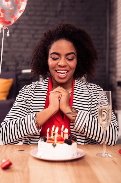 Estoy listo. Mujer positiva alegre preparándose para soplar las velas mientras pide un deseo