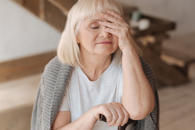 Estoy tan cansado. Triste y agradable anciana que cierra los ojos y se toca la frente mientras se siente cansada