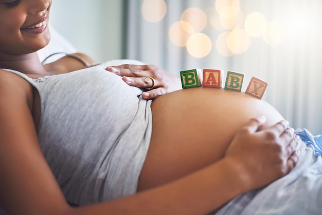 Estoy tan lista para ser mamá Captura recortada de una mujer embarazada con bloques de madera en su vientre que deletrean la palabra bebé