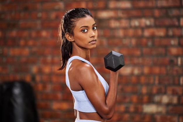 Estoy trabajando para convertirme en la mejor versión de mí mismo Foto de una joven deportista haciendo ejercicio con pesas en el gimnasio