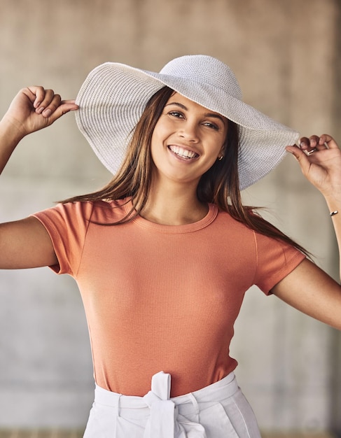 Estoy trabajando en un estreno mundial Retrato de una mujer joven y atractiva con un sombrero para el sol posando sobre un fondo urbano