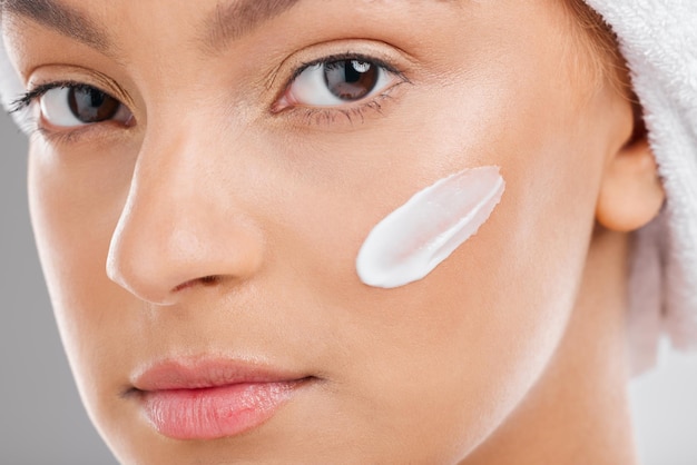 Estoy tratando de honrar mi piel Foto de una mujer joven y atractiva que se aplica crema hidratante en la cara contra un fondo de estudio