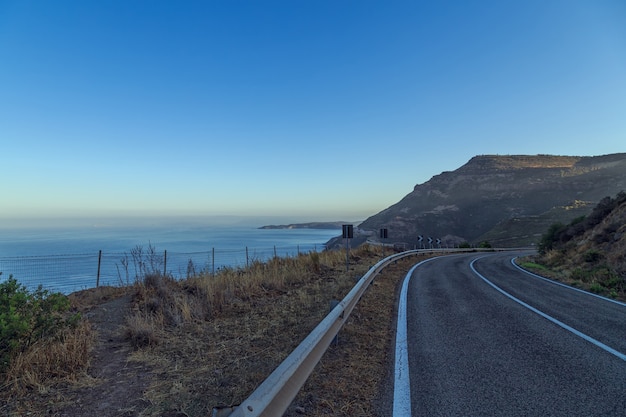 Estrada à beira-mar com céu azul em dia claro.