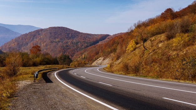 Estrada asfaltada curva vazia por montanhas