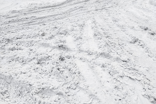 Estrada branca não limpa coberta de neve, vestígios de rodas de carro.