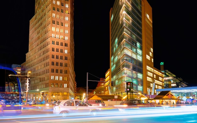 Foto estrada com tráfego de carros na estação bahnhof e arquitetura moderna de construção na praça potsdamer platz, no centro da cidade alemã, em berlim, na alemanha. à noite