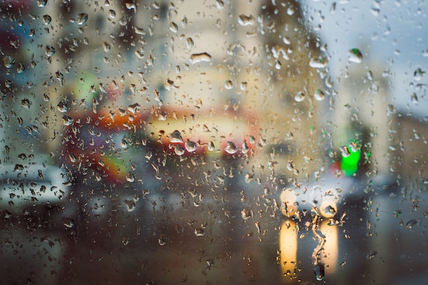 Estrada da cidade vista através da chuva cai no pára-brisa do carro