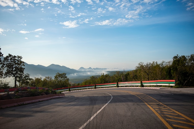 Estrada da curva que conduz um carro na estrada da montanha para baixo. nuvem bonita do céu azul da curva dramática com névoa da névoa na manhã.