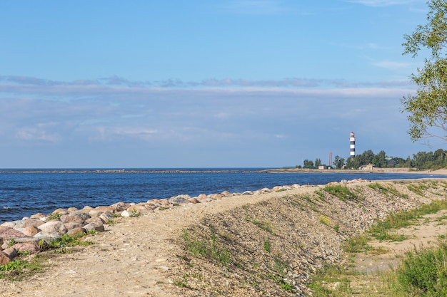 estrada de areia ao longo do mar e à distância um farol