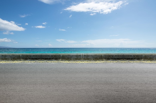 Estrada de asfalto com vista para o mar e fundo de céu azul