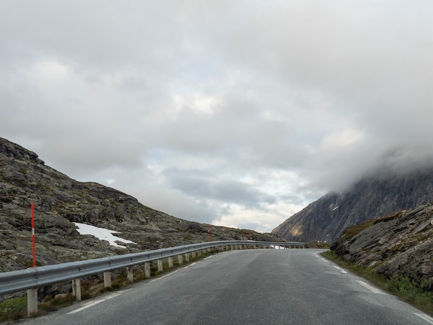 Foto estrada de asfalto estreita no alto das montanhas em um dia nublado e cinzento