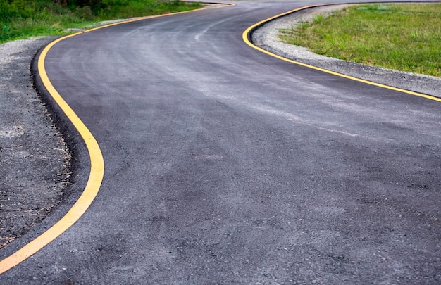 Estrada de asfalto preto curva com linha amarela