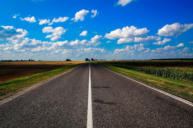 Estrada de campo vazia em meio à paisagem contra o céu azul