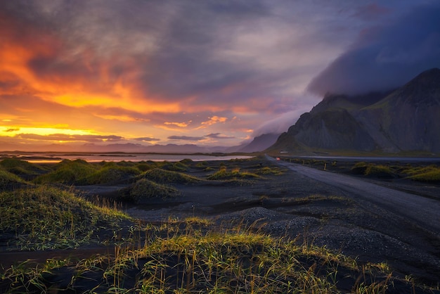 Estrada de cascalho ao pôr do sol com a montanha Vestrahorn ao fundo Islândia