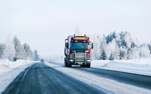 Estrada de inverno com neve. Caminhão na Finlândia. Carro de camião e paisagem fria da Lapónia. Floresta da Europa. Passeio pela estrada da cidade finlandesa. Estrada e rota viagem de rua nevada. Entrega na condução em declive